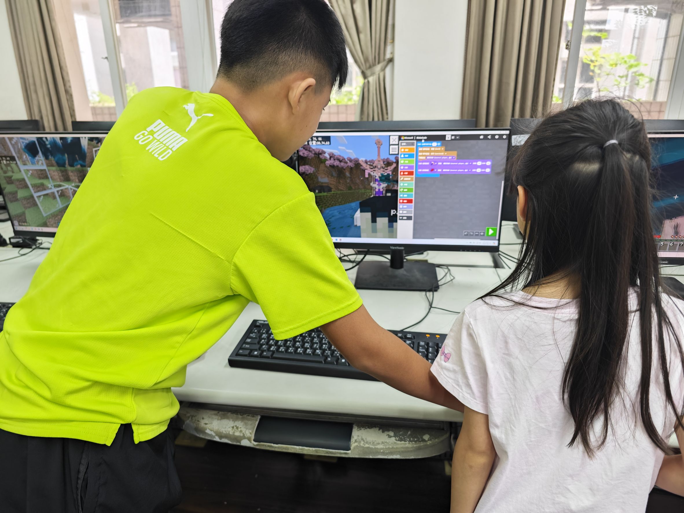 星圖創學程式營隊學員共同在電腦螢幕前討論程式碼與進行 Debug 除錯，培養軟體工程師解決問題的韌性與協作精神