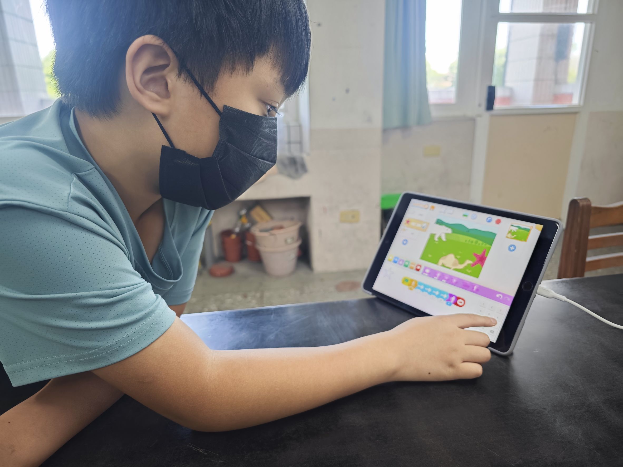 低年級學員操作 ScratchJr 拖曳指令積木，親手打造包含跳躍、碰撞等動作機制的經典遊戲闖關畫面與生態故事